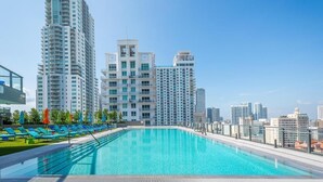Piscina no terraço com paisagem urbana ao fundo.