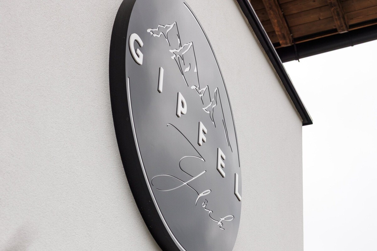 A circular sign with the text 'GIPFEL' and a signature on a building's exterior wall.