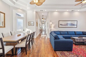 A modern living room with a blue sectional sofa, wooden dining table with chairs, and a patterned rug. - Stylish, Central Nola Getaway! Parking+Street Car (New Orleans)
