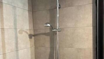A shower with a handheld showerhead and a wall-mounted faucet.