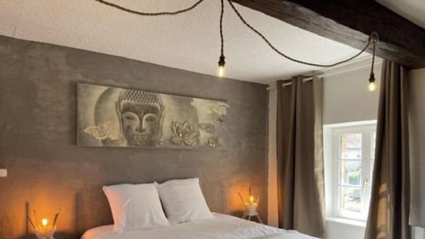 Un dormitorio con una cama grande, dos lámparas de noche, una obra de arte en la pared y una ventana con cortinas.