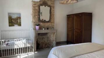 Una camera da letto con un letto bianco, un armadio in legno, un camino in pietra e un termosifone bianco.