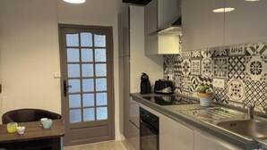 Una cocina moderna con encimera de vidrio, pileta de acero inoxidable y salpicadero con diseño.