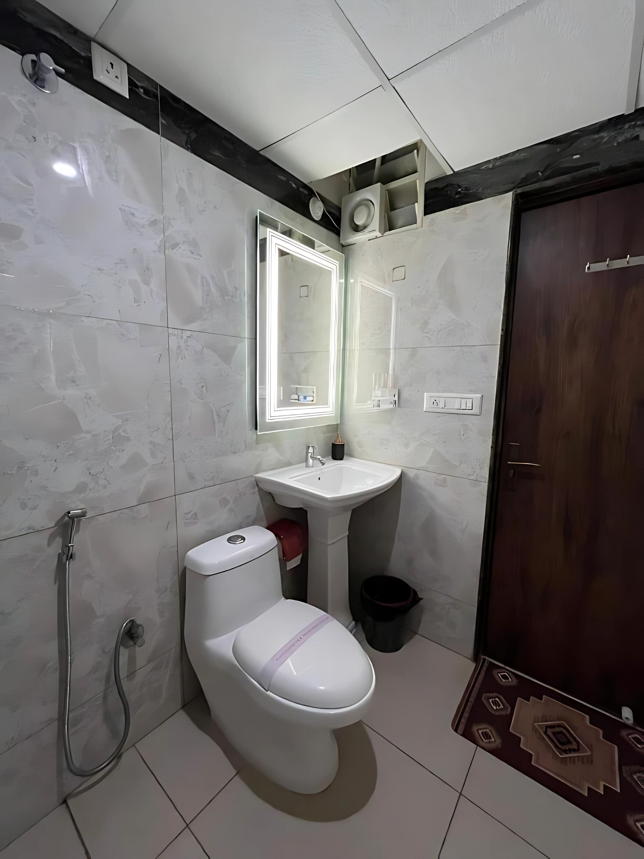 Et badeværelse med toilet, håndvask, spejl og brusebad.