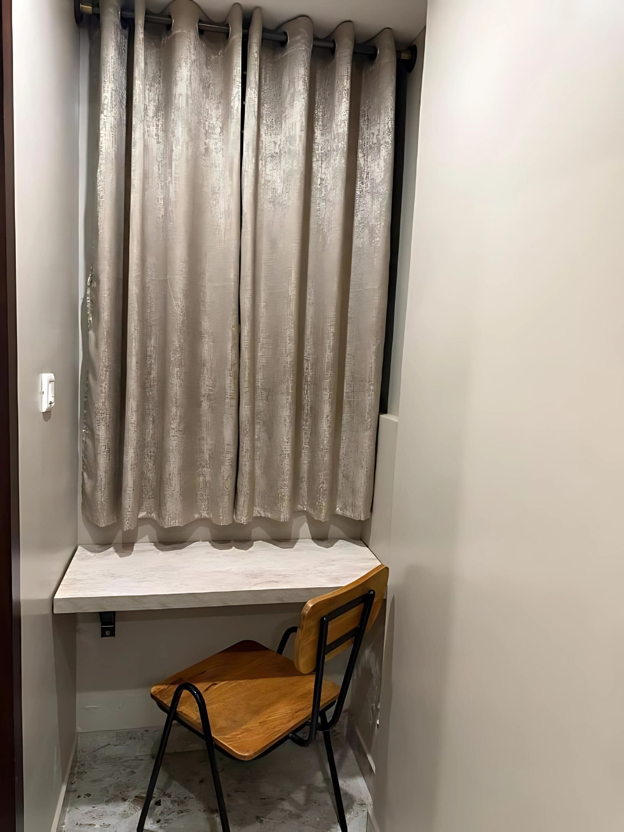 A corner room with a wooden chair, a small table, and a curtain.