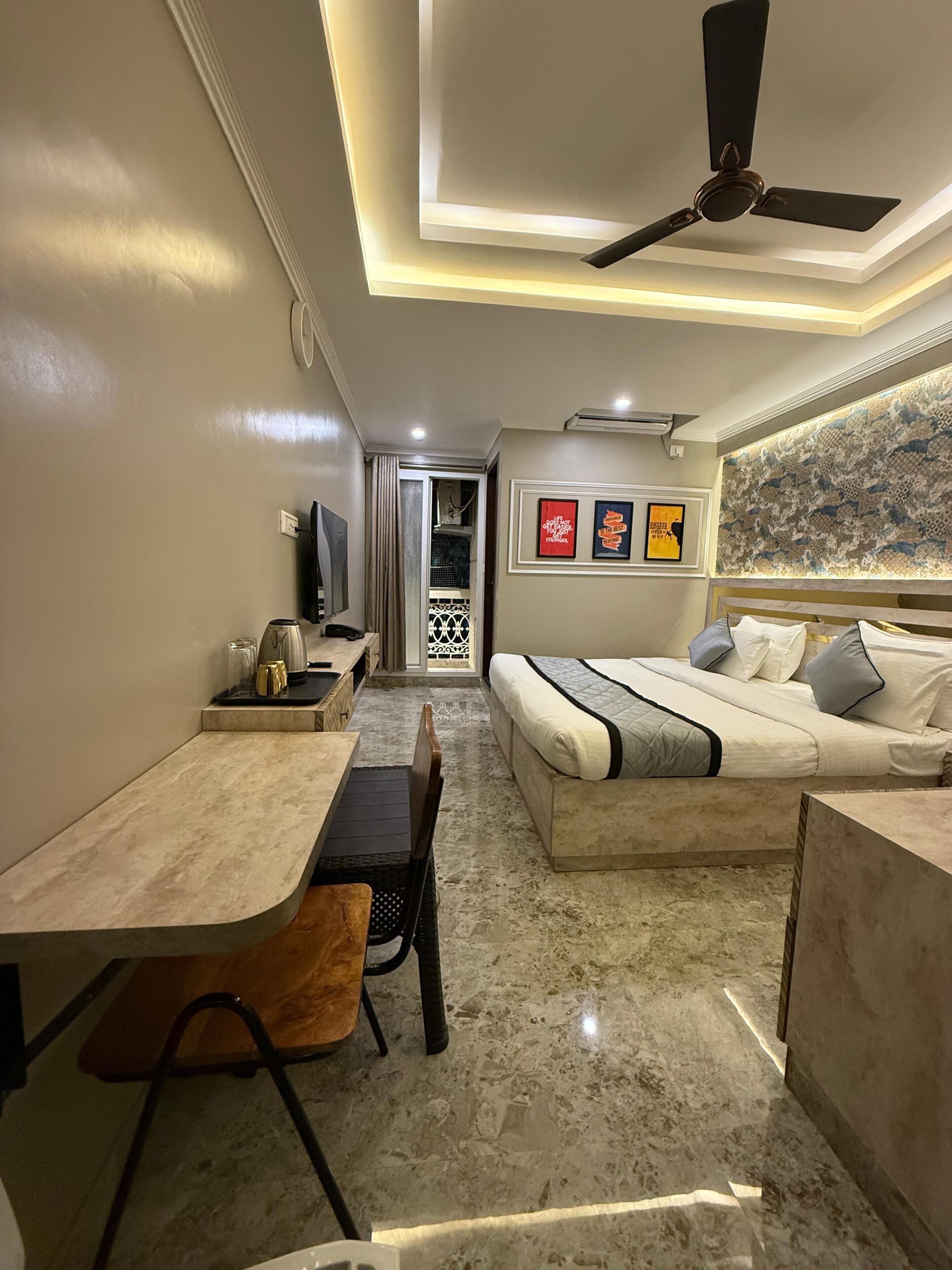 A modern bedroom with a bed, a desk, and a ceiling fan.