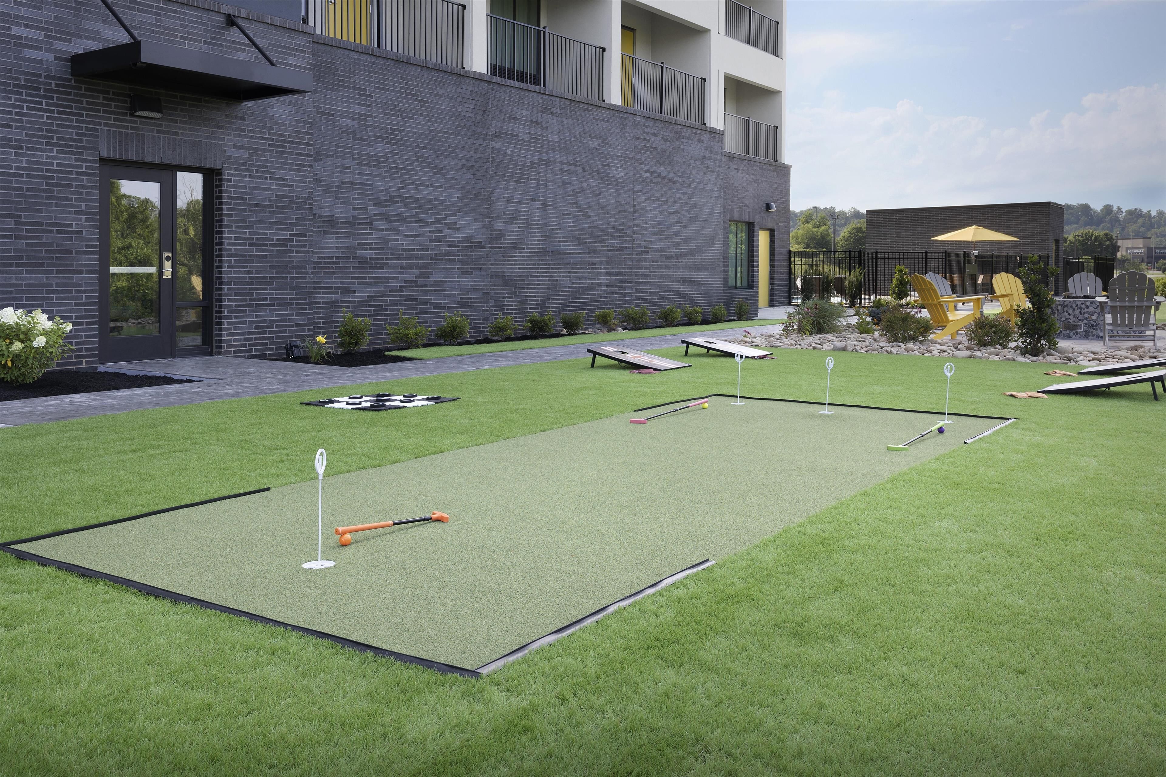 A modern building with a brick facade, a flat roof, and a small patio area with artificial grass and outdoor furniture.