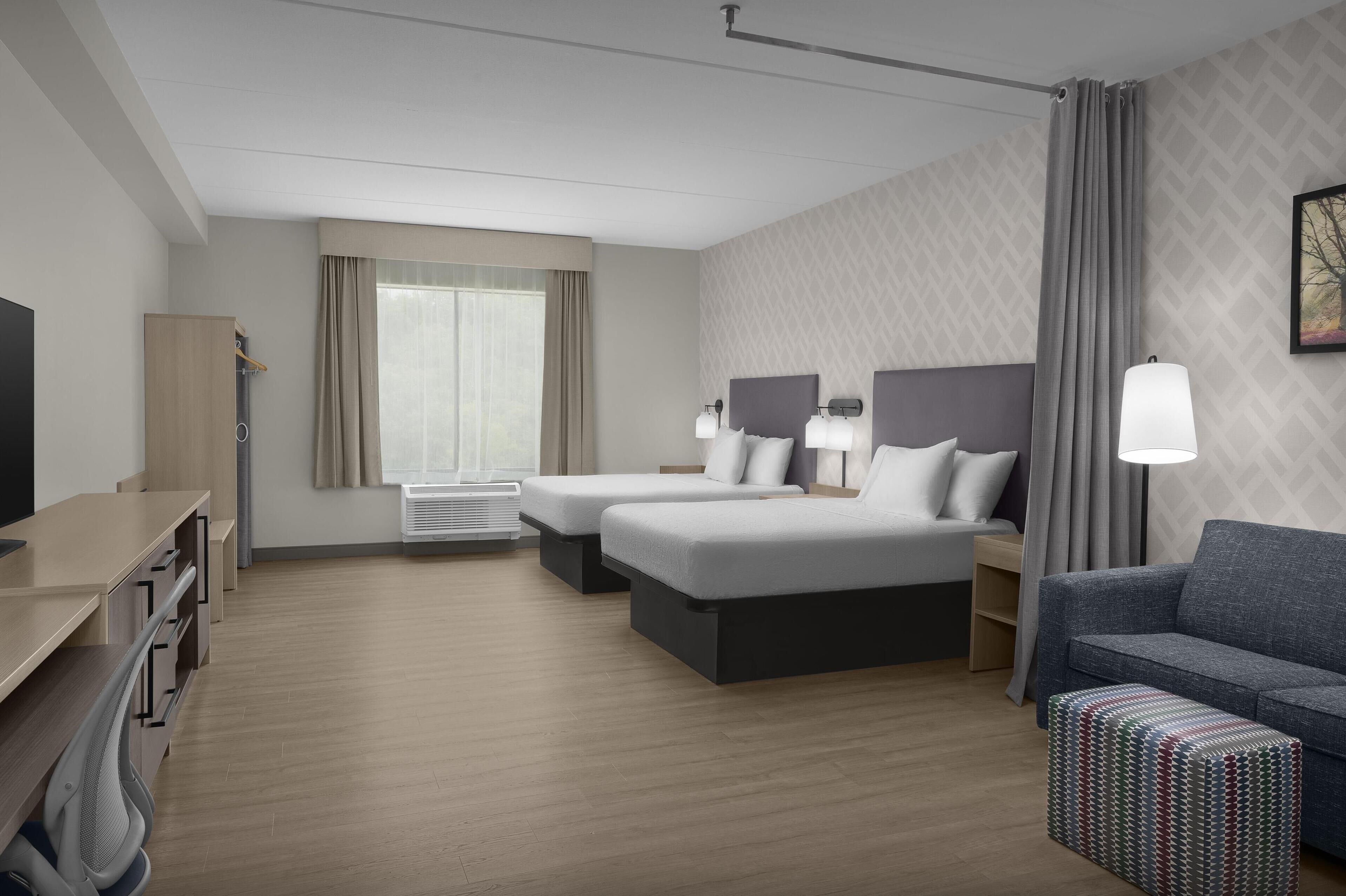A hotel room with a bed, a sofa, a desk, and a TV.