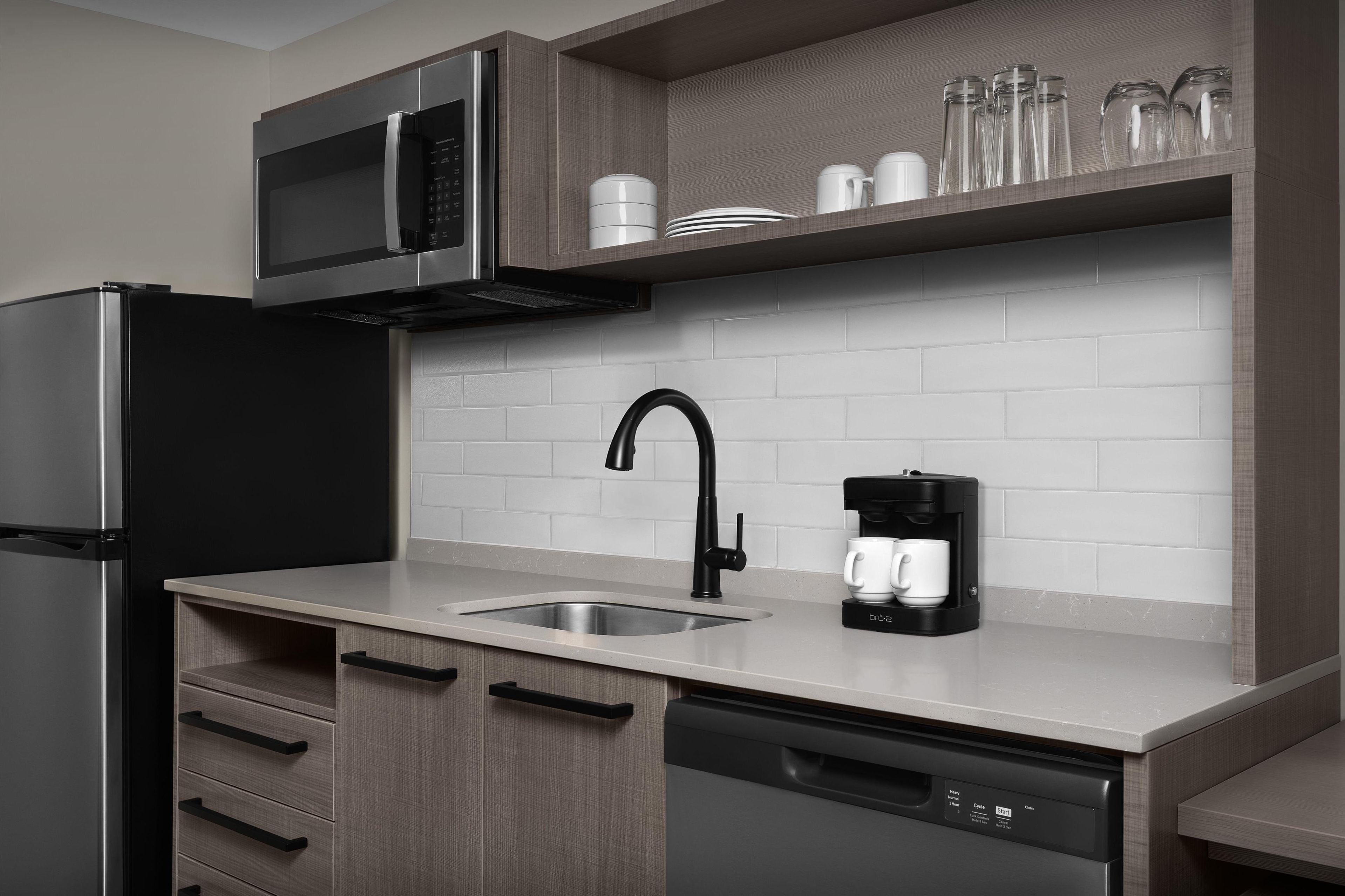 A modern kitchen with a stainless steel refrigerator, a microwave, a coffee maker, and a dishwasher.