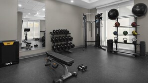 Un gimnasio con banco, mancuernas, kettelbells y pelotas de ejercicio.