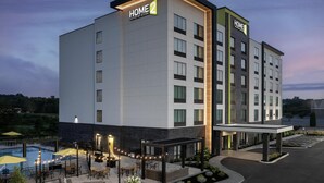 Un moderno edificio de hotel con un letrero que dice "HOME 2" y "Suites by Hilton".