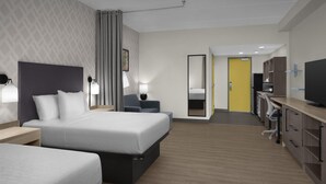Una habitación de hotel con dos camas, un escritorio con silla, una televisión y un espejo.