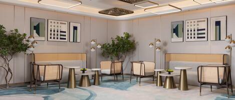 A modern hotel lobby with a seating area, decorative ceiling lights, and wall art.
