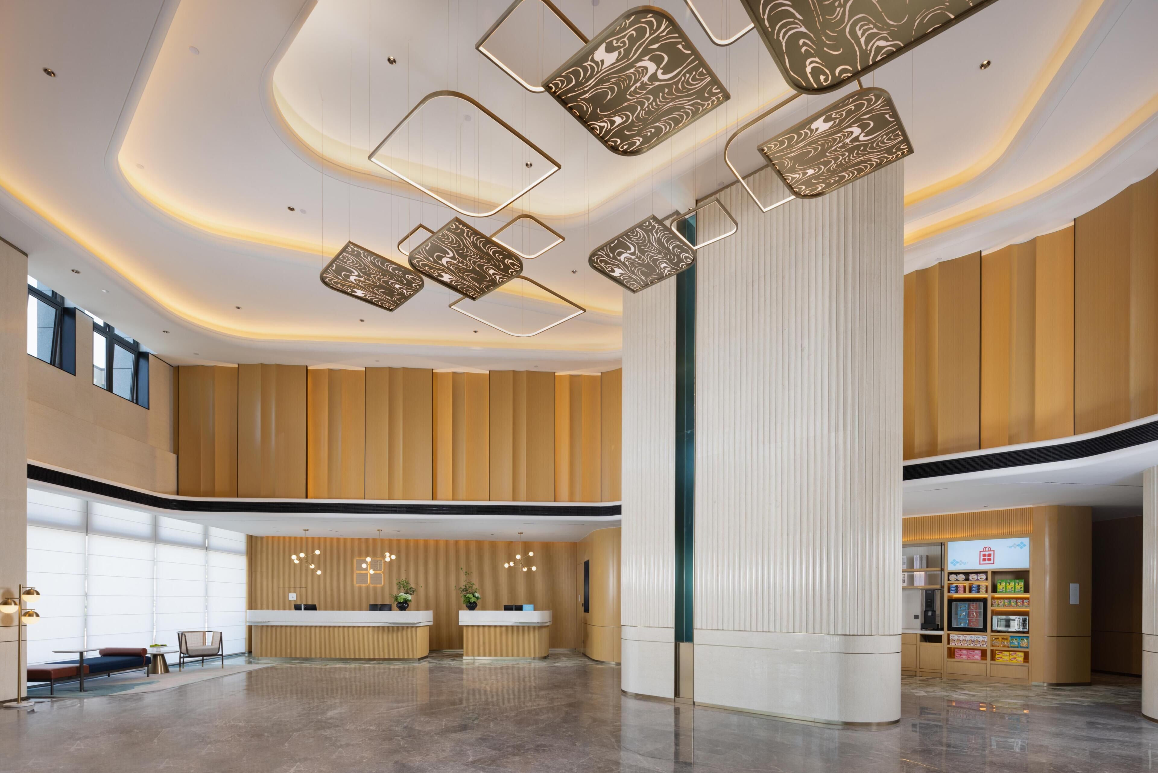 A spacious lobby with a reception desk, seating area, and a large column.