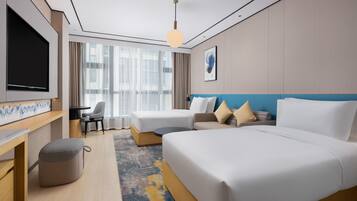 A hotel room with a bed, a desk, a chair, a TV, and a window with curtains.