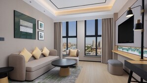 Una sala de estar moderna con sofá, mesa de centro, reposapiés y televisor.