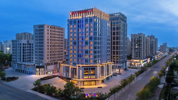 Un hotel moderno con una fachada de vidrio destacada, rodeado de otros edificios altos.