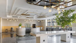 Un espacio de oficina moderno con un mostrador de recepción central, una larga mesa compartida y un amplio ventanal que proporciona luz natural.
