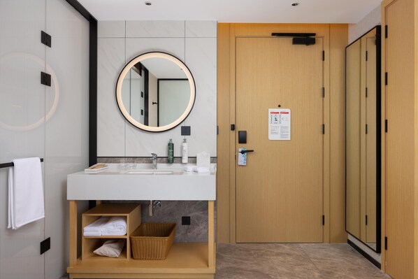 A modern bathroom with a round mirror, a sink, and a wooden cabinet with a basket.