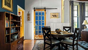 Un coin repas avec une table ronde, des chaises, un tapis à motifs et une bibliothèque.