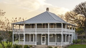 Une maison à deux étages dotée d’un balcon, d’un porche et d’un chemin de pierre menant à l’entrée.