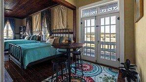 Une pièce comprenant un lit, une table avec deux chaises, un tapis à motifs et une porte donnant sur une vue agréable.