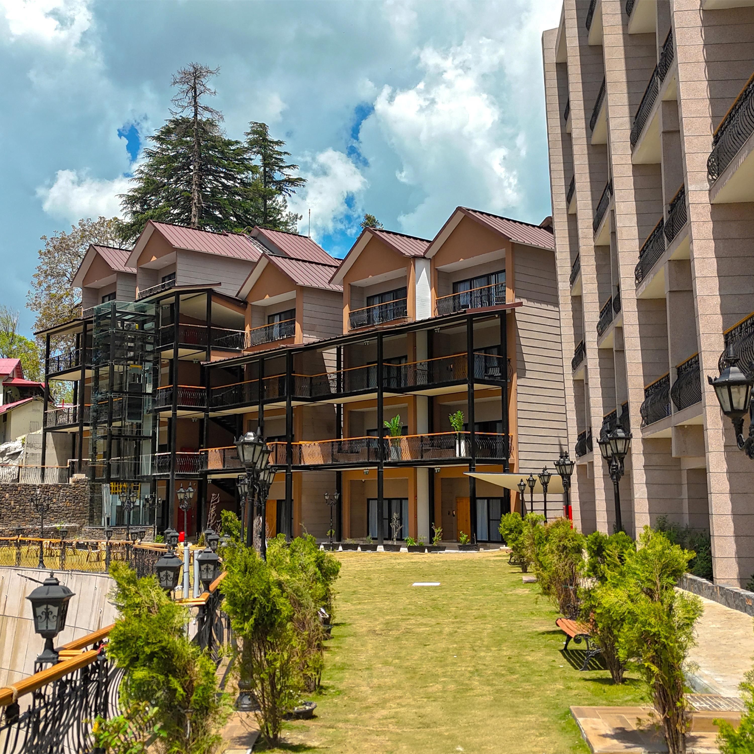 Un hotel a più piani con balconi, un cortile centrale e vista su una montagna.