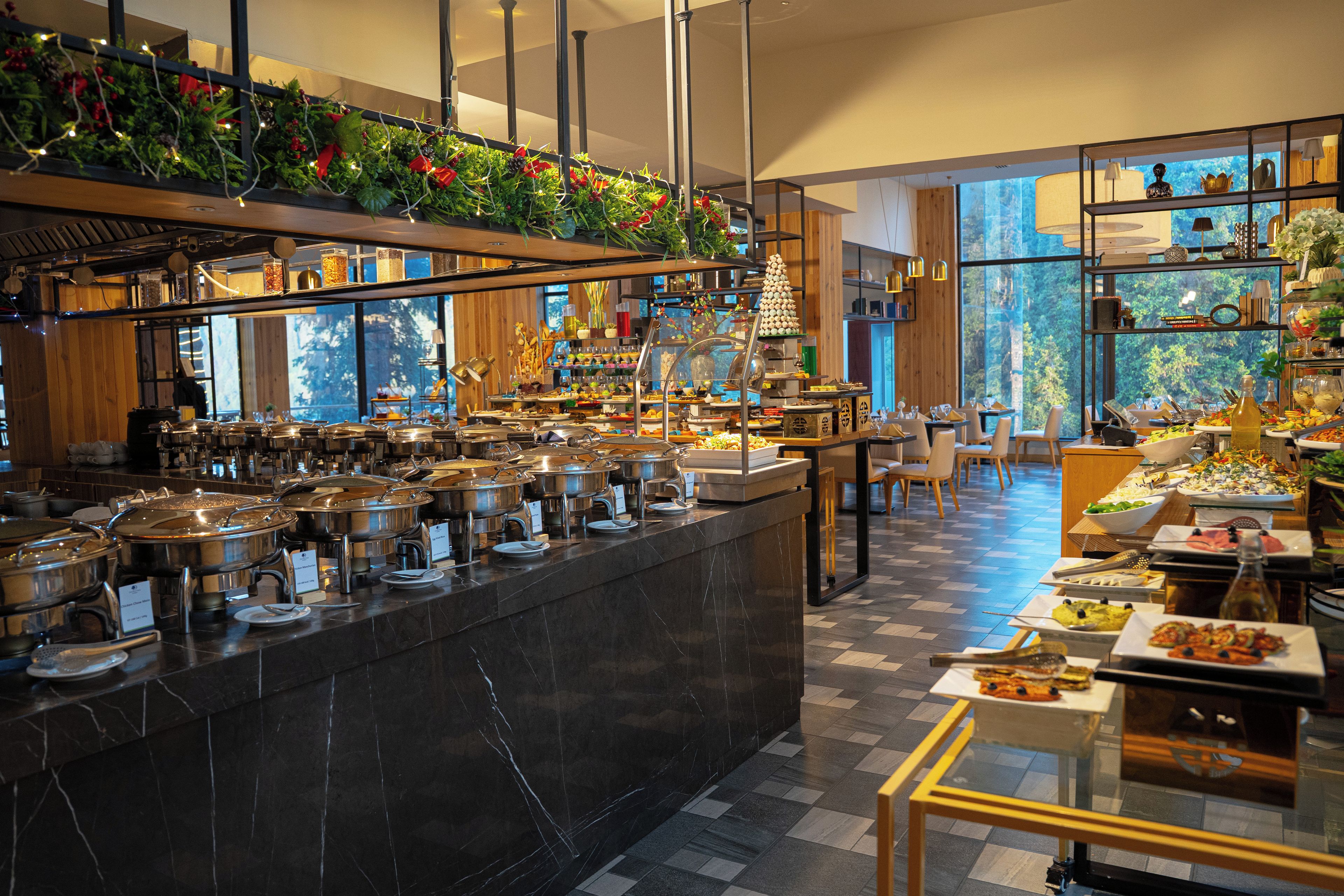 Un espace buffet proposant différents stands de restauration, une grande variété de plats et une vue sur l’extérieur grâce à de larges fenêtres.