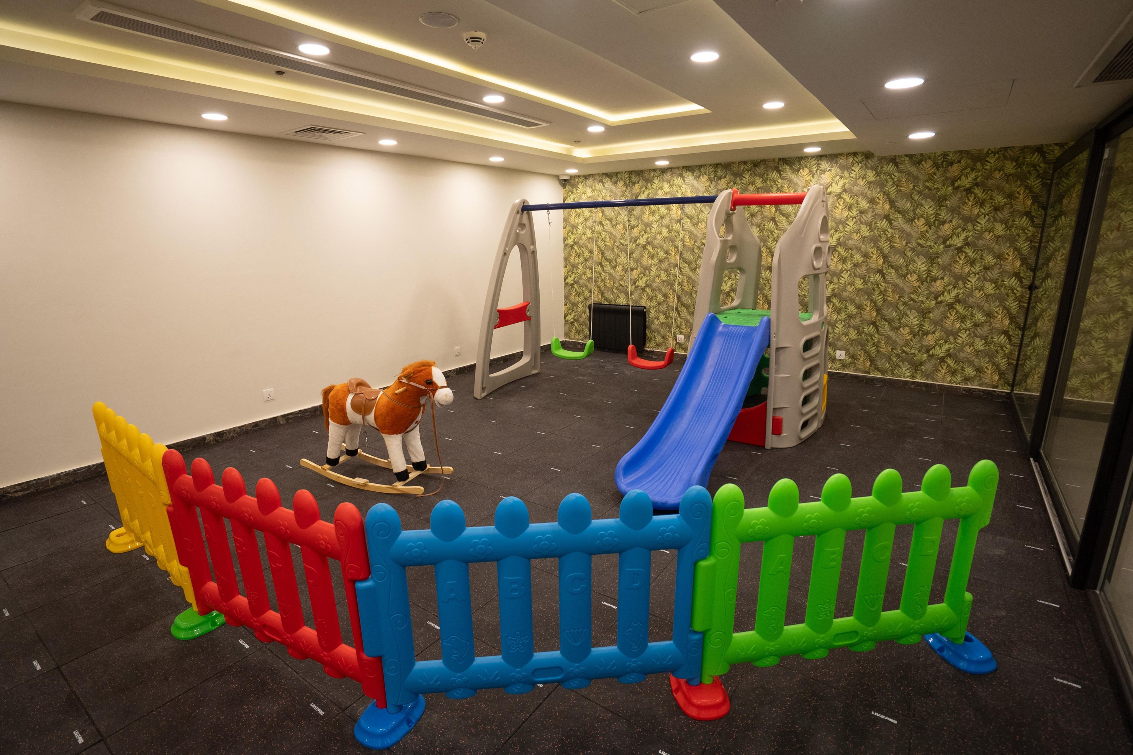 A play area with a swing set, a slide, and a rocking horse.