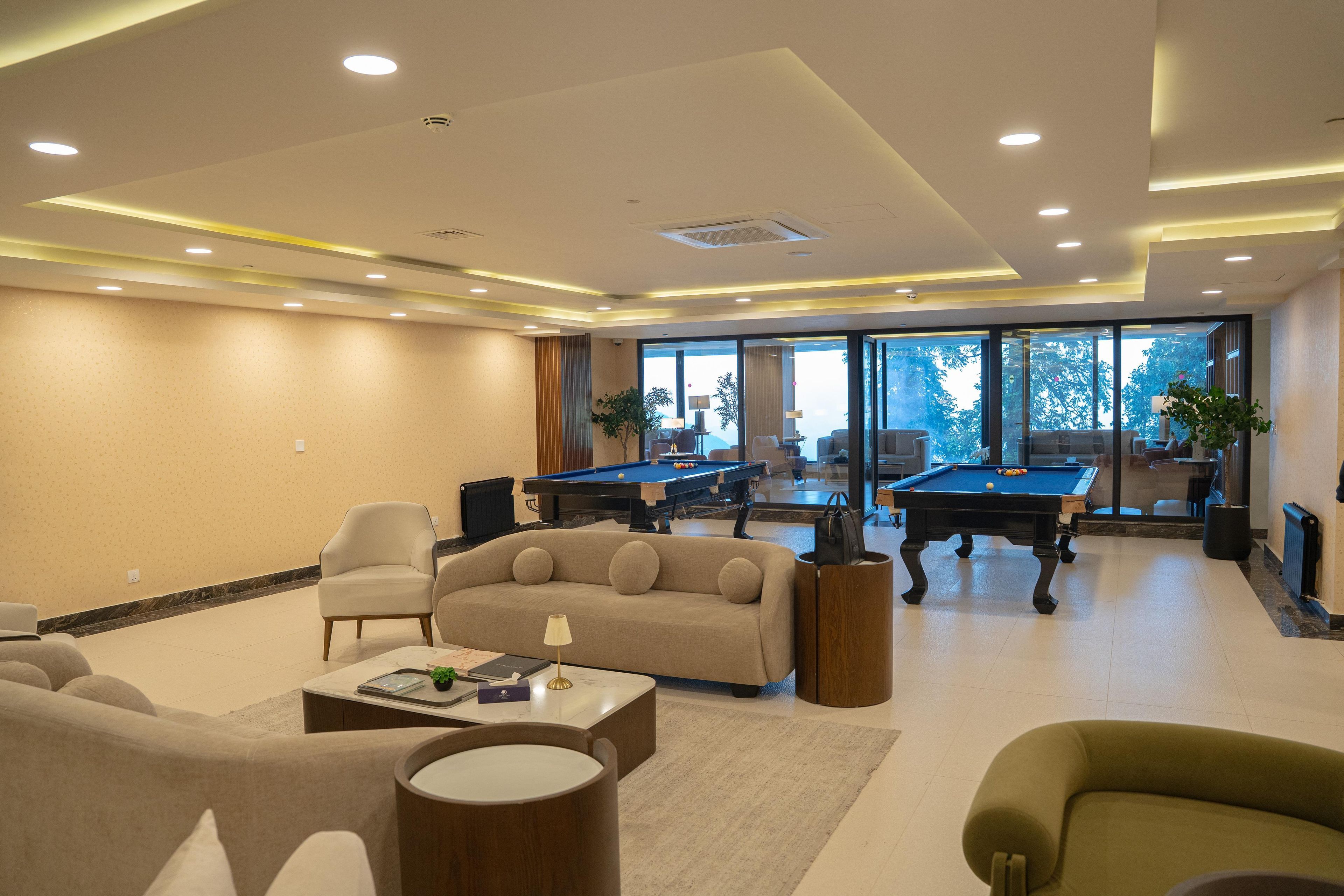 A spacious indoor area with a pool table, sofas, and a coffee table.