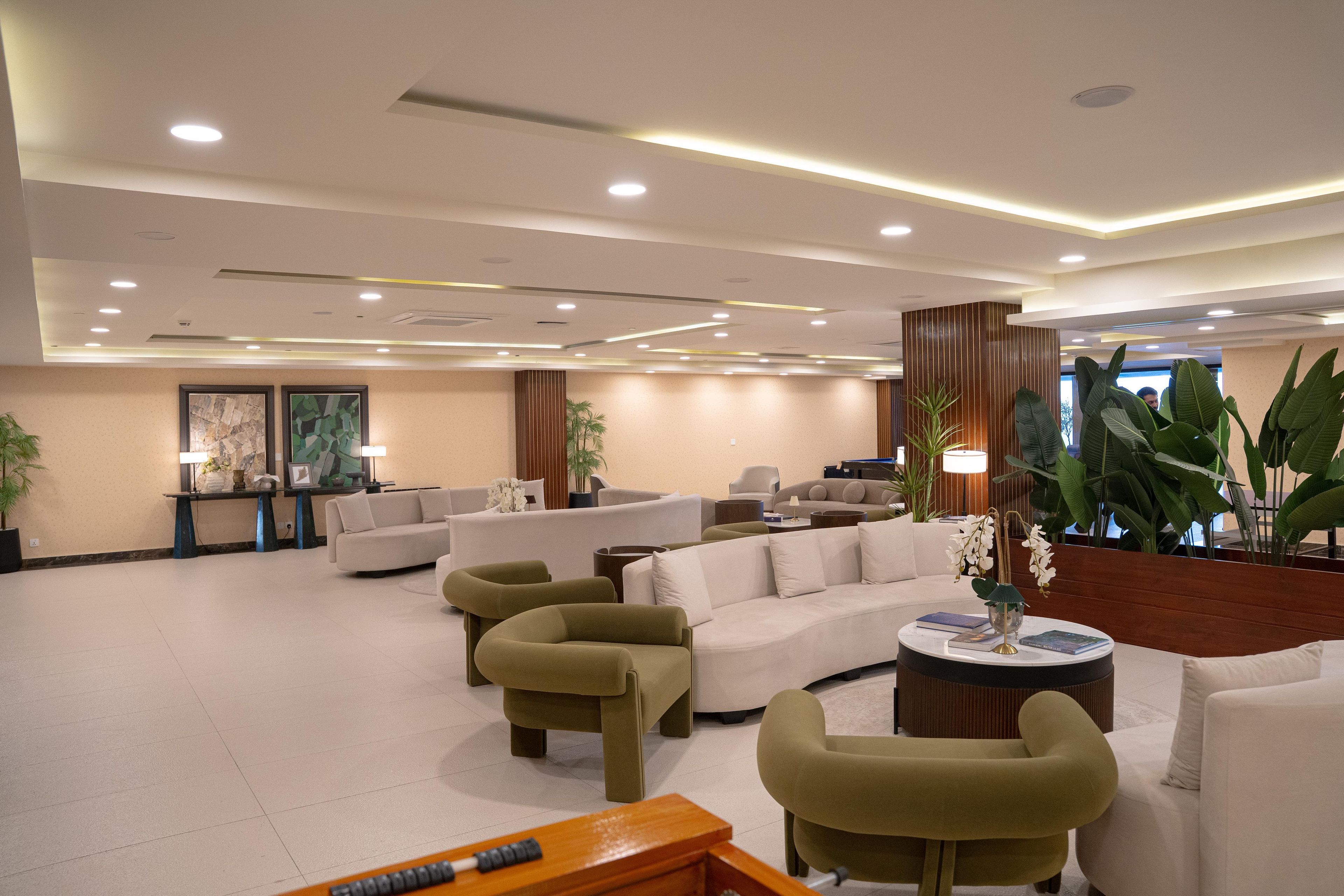 A spacious lobby with multiple seating areas, including sofas and armchairs, a coffee table, and a reception desk.
