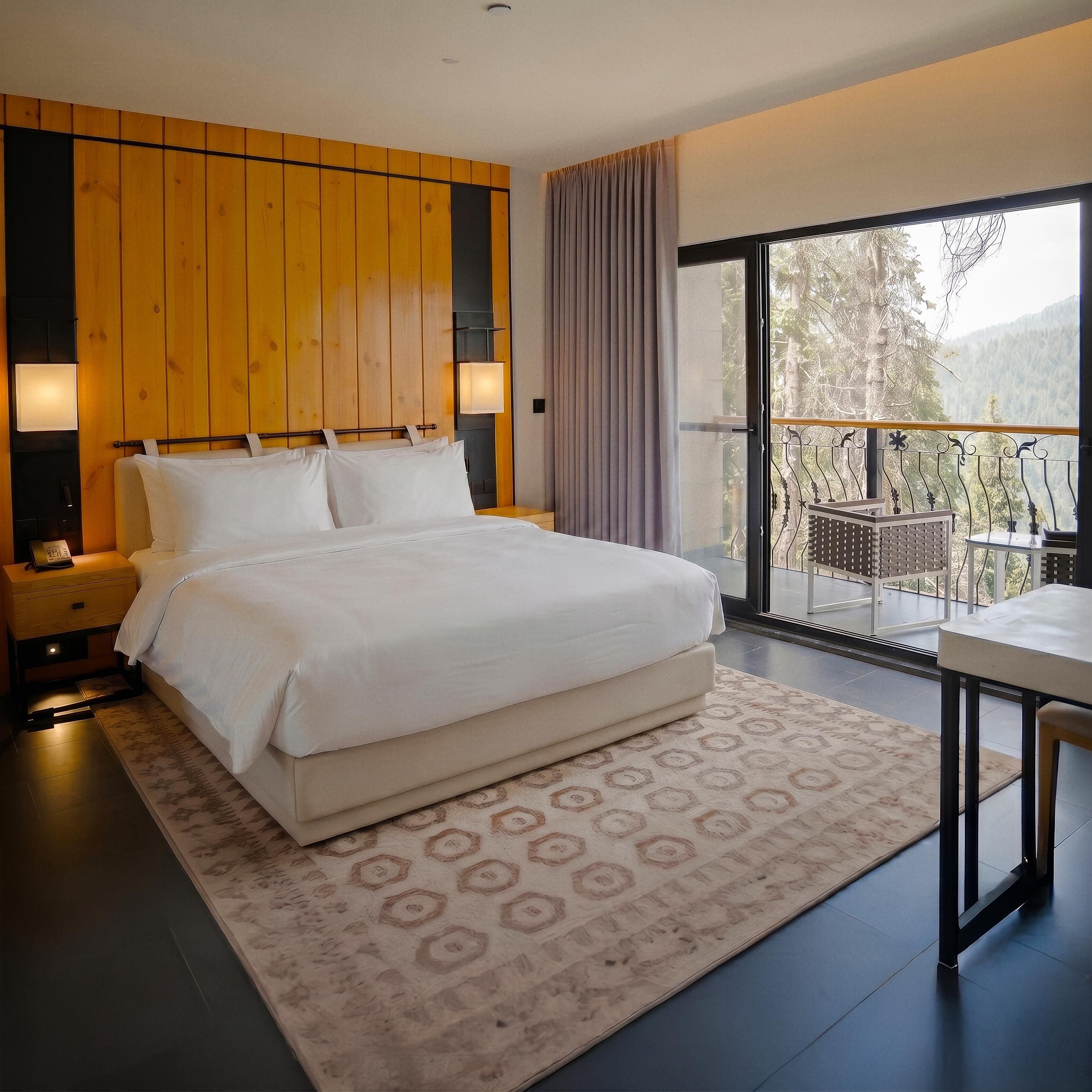 A modern bedroom with a large bed, wooden panel wall, bedside lamps, and a balcony with a view.