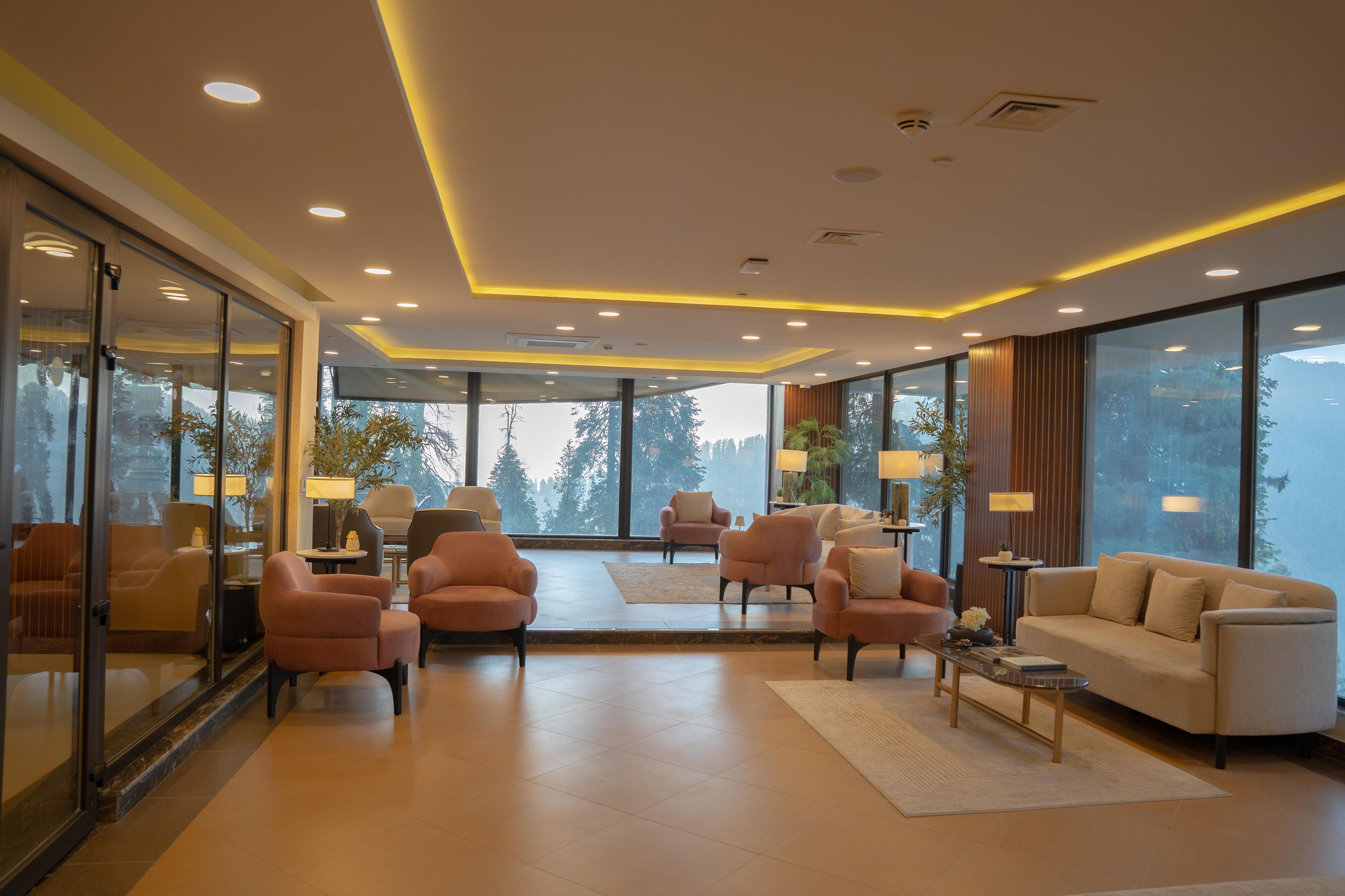 A modern living room with a large window, sofas, armchairs, and a coffee table.