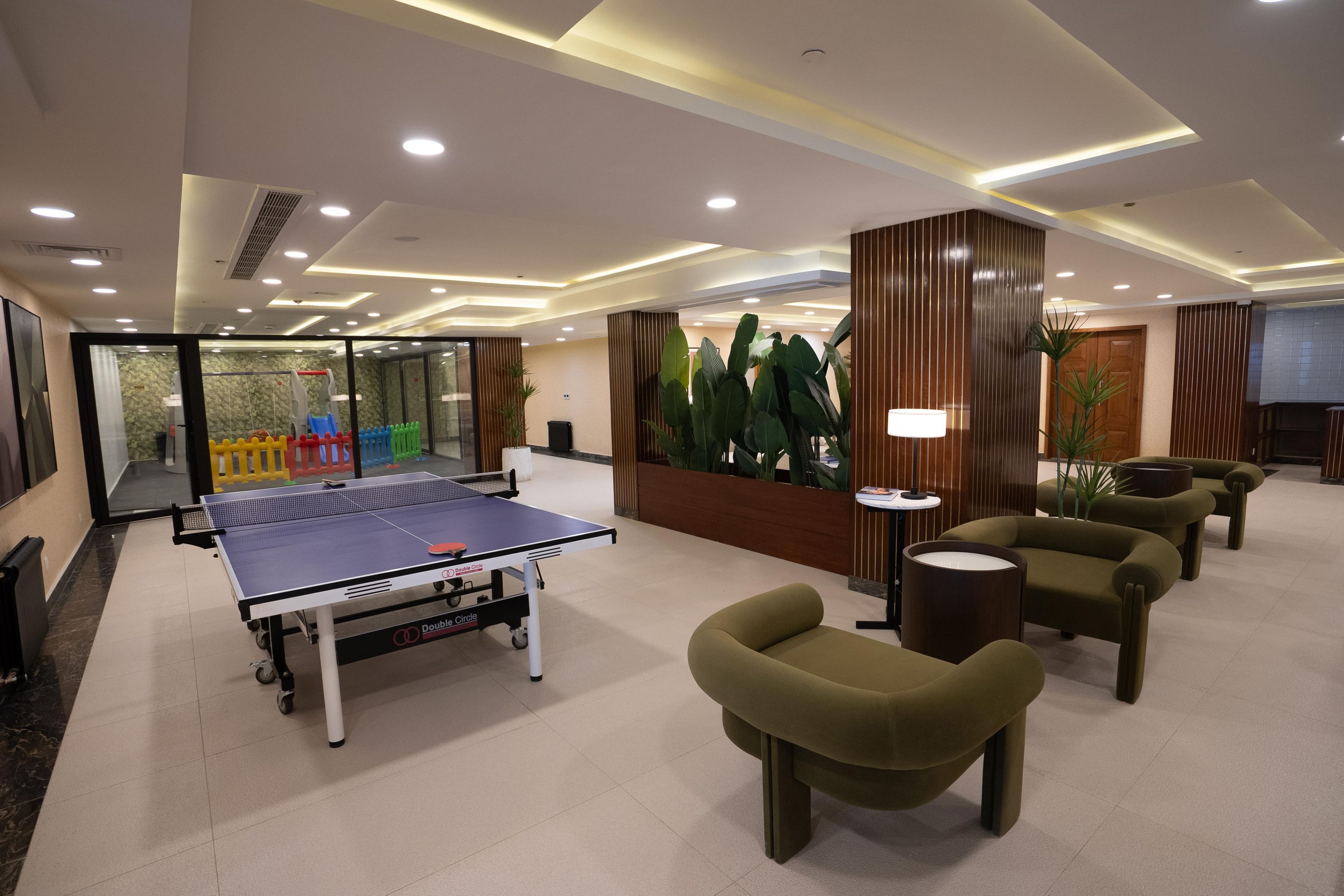 Habitación con mesa de ping pong, zona de estar y recepción.