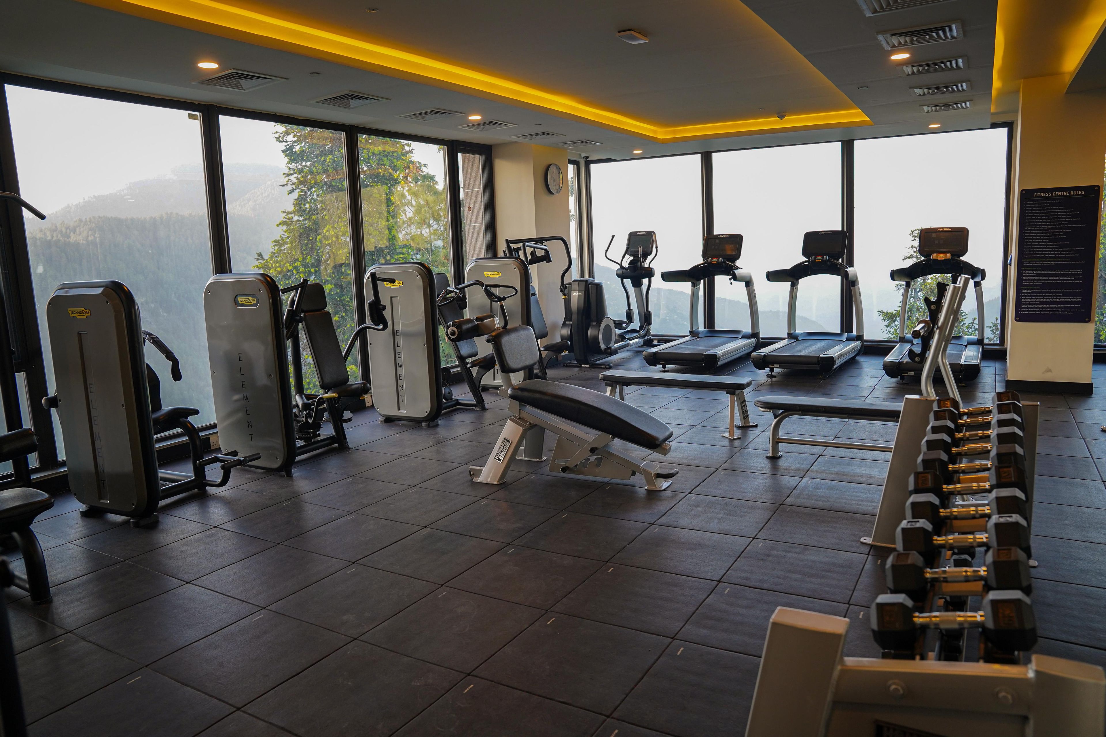 A gym with various exercise equipment, large windows, and a view of mountains.