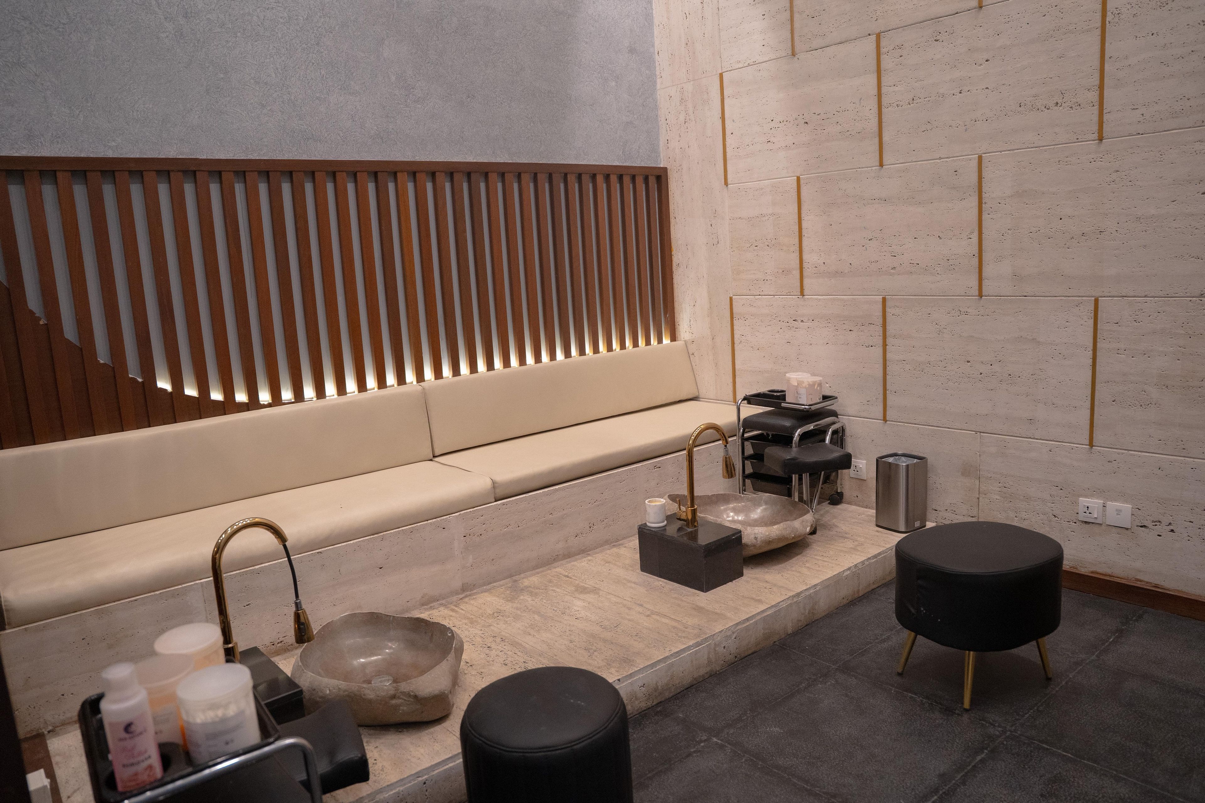 Un baño moderno con un lavamanos de piedra, taburetes negros y una ventana de madera con listones.