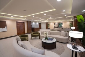 A modern hotel lobby with a curved sofa, a round coffee table, and a TV mounted on the wall. - Doubletree By Hilton Nathiagali (Abbottabad)