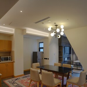 A modern kitchen with a dining area, featuring a central table with chairs, a microwave, and a refrigerator. - Doubletree By Hilton Nathiagali (Abbottabad)