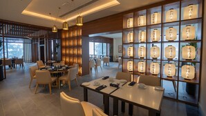 A modern dining area with tables and chairs, a decorative wall with illuminated panels, and a view of the outdoors. - Doubletree By Hilton Nathiagali (Abbottabad)