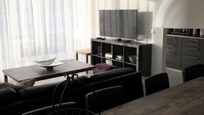 A modern living room with a dining area, a TV, and a kitchen. - Halllandsnes Apartments (Akureyri)
