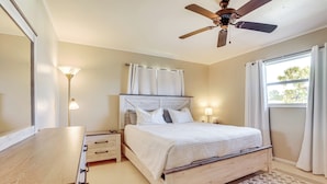 A bedroom with a wooden bed, bedside lamps, a ceiling fan, and a window with curtains. - 4 Mi to Historic Dtwn Venice: Home w/ Heated Pool! (Venice)