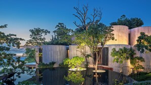 A modern building with cylindrical concrete structures, a reflective water feature, and surrounding greenery. - Vows Villa Beachfront (Koh Samui)