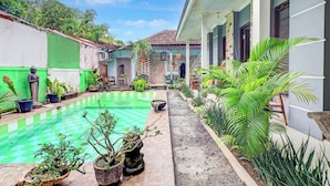 A courtyard with a checkered pool, potted plants, and a building with a tiled roof. - Collection O Sanur Near Bali Exotic Marine Park (Denpasar)