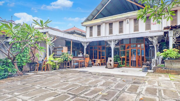 A traditional building with a covered courtyard, wooden furniture, and potted plants. - Collection O Sanur Near Bali Exotic Marine Park (Denpasar)