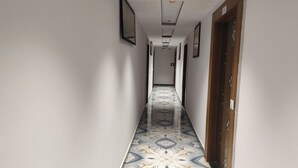En hall med ett mönstrat golv, inramade tavlor på väggarna och en dörr med en dekorativ design.