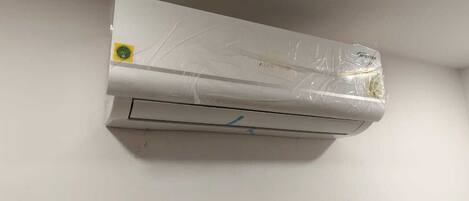 A white air conditioning unit mounted on a plain wall.