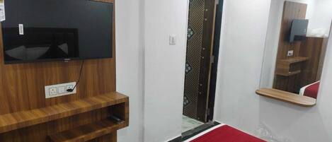 Un dormitorio con un televisor montado en un panel de madera, un espejo y una alfombra roja.