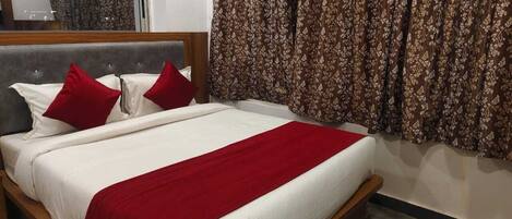 A neatly made bed with white and red bedding, a wooden headboard, and a red throw blanket.