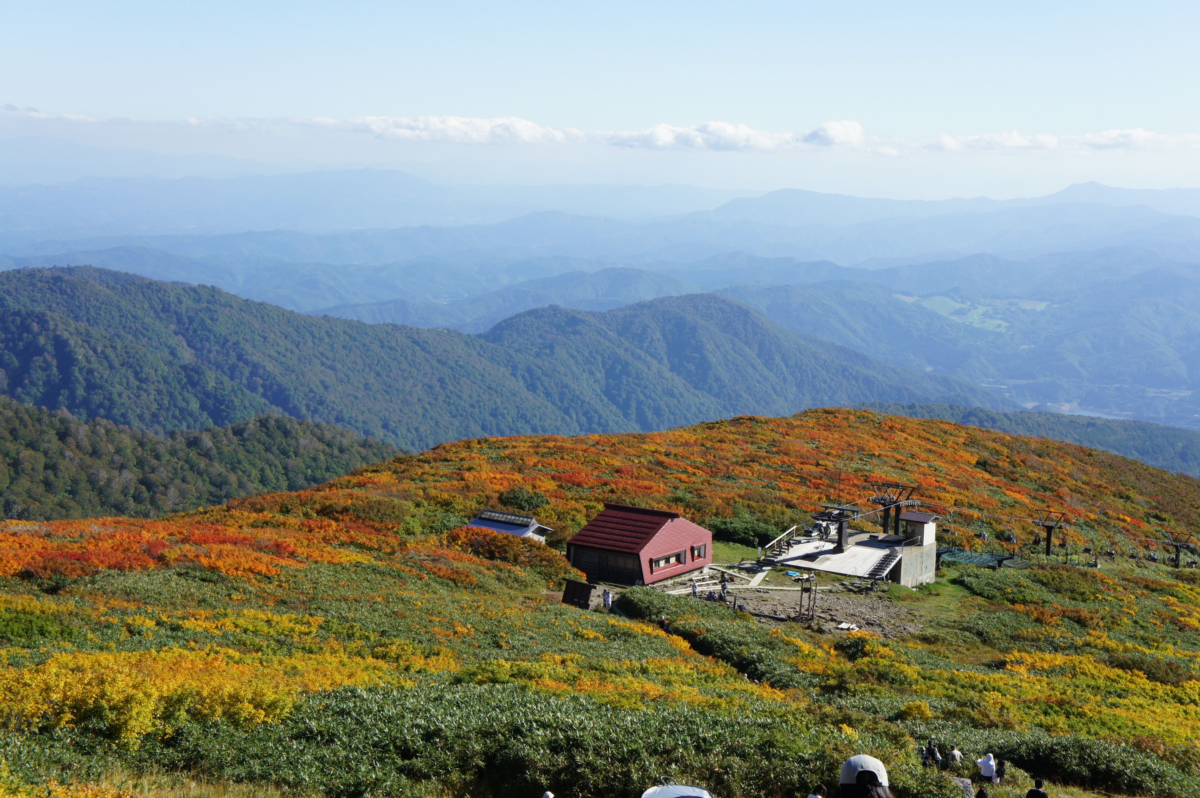 Paisagem montanhosa com um pequeno edifício de telhado vermelho e um conjunto de painéis solares.