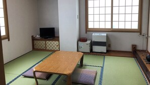 A traditional Japanese room with tatami flooring, a wooden table, a television, and a window with a grid pattern. - Gassan no yado kasiwaya (Nishikawa)